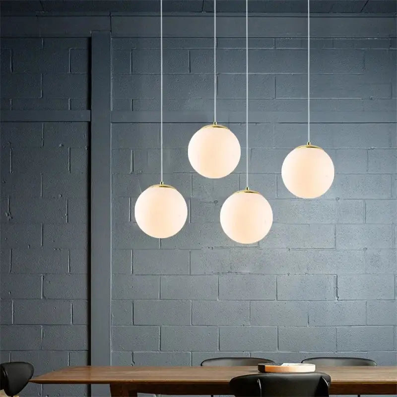 Four frosted glass ball pendant lights with gold fixtures from decorbites hanging against dark gray wall for living room decor