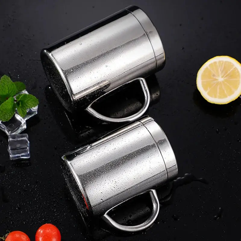 Two sleek stainless steel double wall coffee mugs with shiny metallic finish and integrated handles for travel use