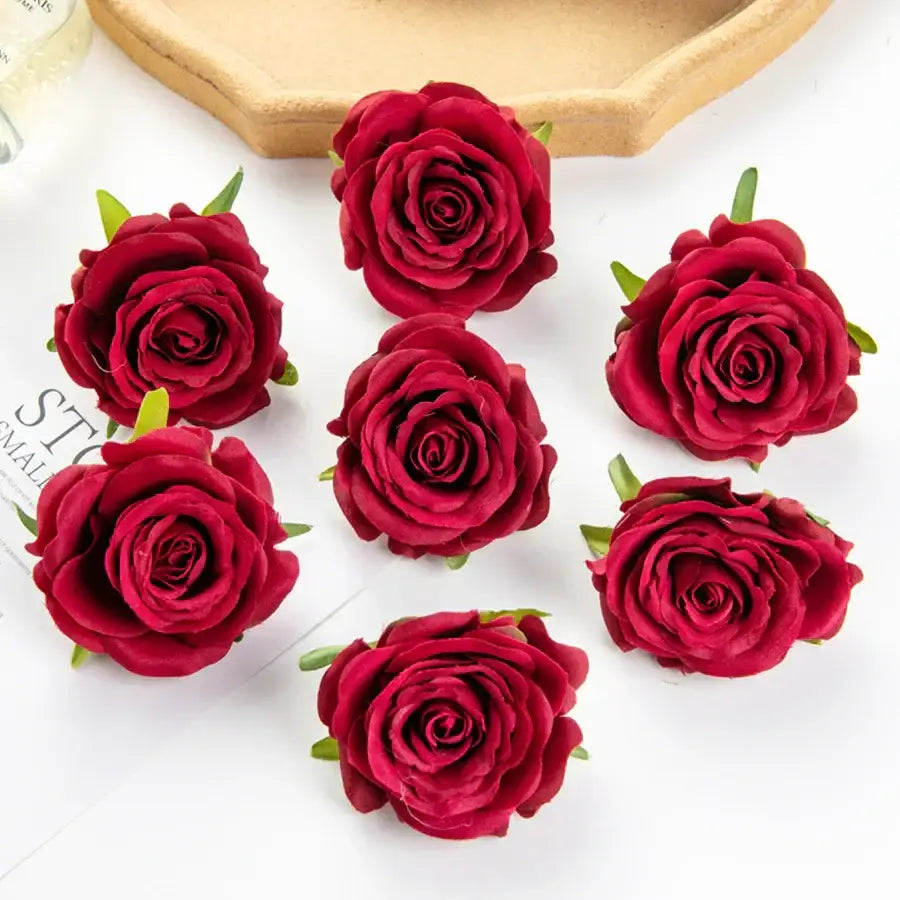 Deep red artificial flowers with detailed petal layers and green stems complement silk blue rose decor for weddings and bedrooms