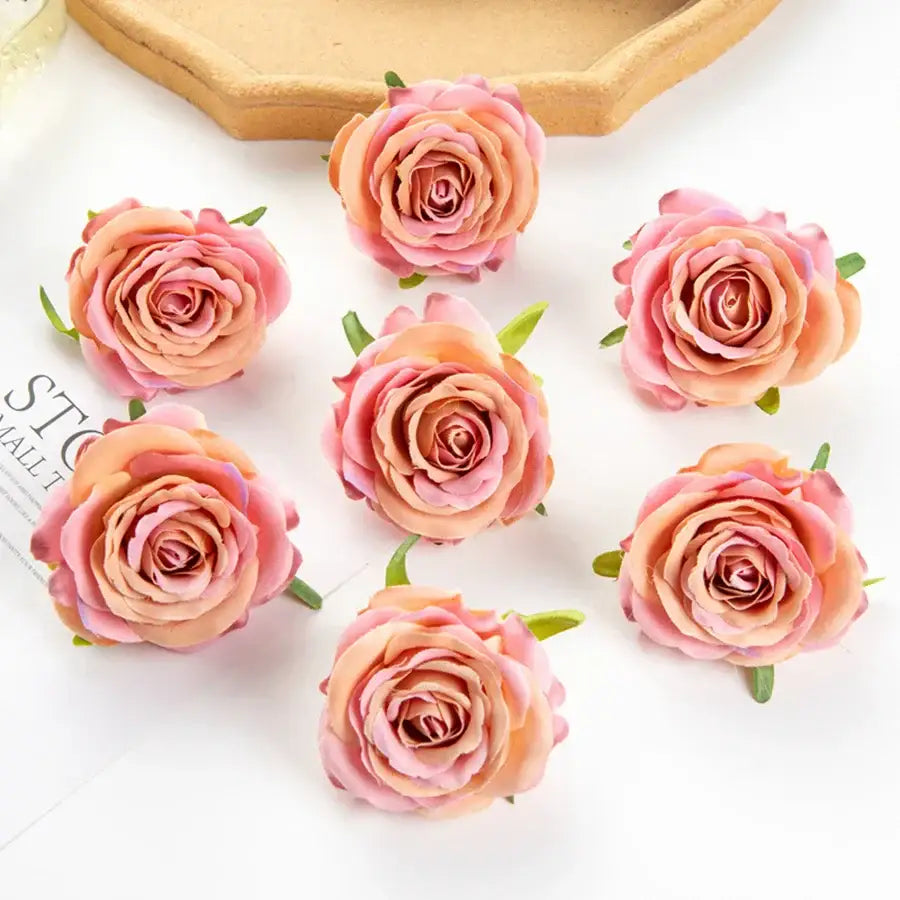 Six artificial peach and pink silk blue roses with green stems arranged on white surface for wedding party decor