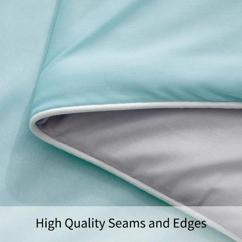 Light blue and gray fabric with white stitching on edge of silky light blue cooling queen quilt for summer use