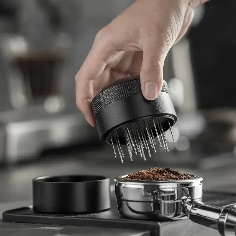 Silver and black decorbites coffee needle distributor with textured grip and fine evenly spaced prongs for espresso preparation