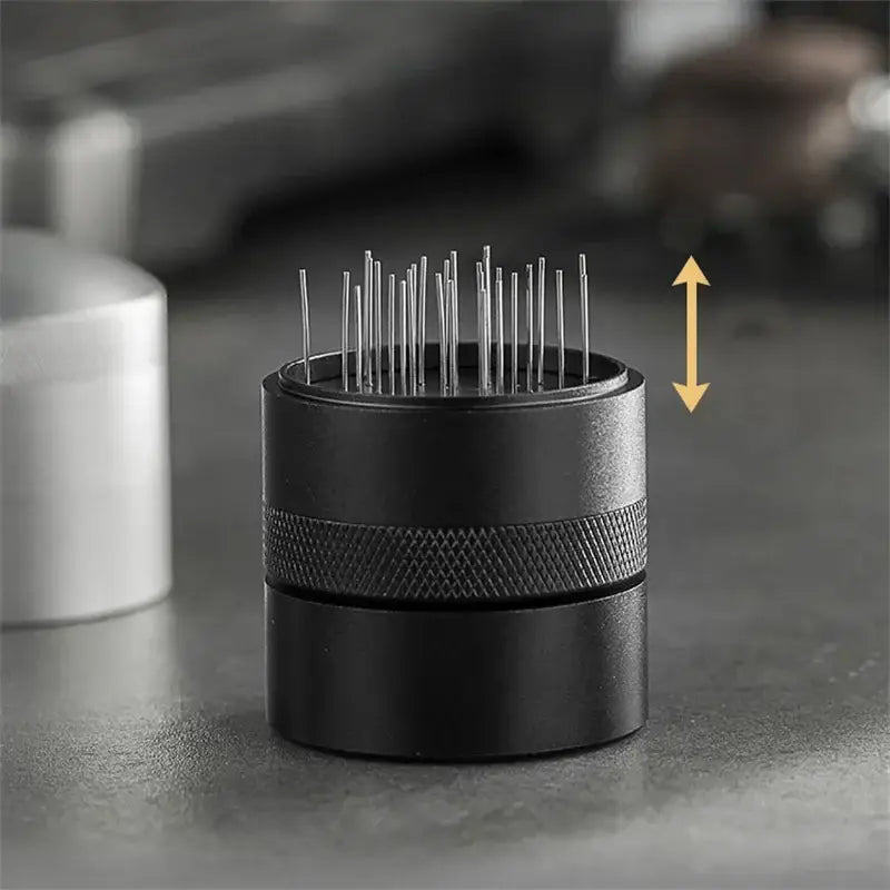 Black cylindrical decorbites coffee needle distributor with textured grip band and multiple silver needles inside