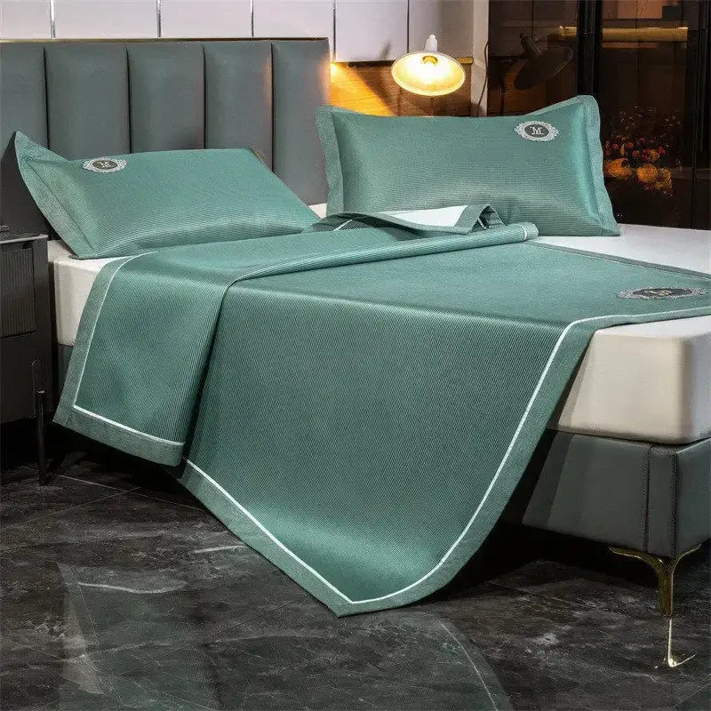 Teal-colored decorbites carbon light cooling bedspread with textured weave white piping and embroidered logos on pillows