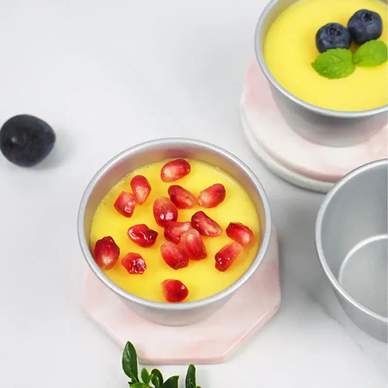Silver carbon steel cake mold filled with yellow custard topped with red pomegranate seeds by decorbites carbon steel