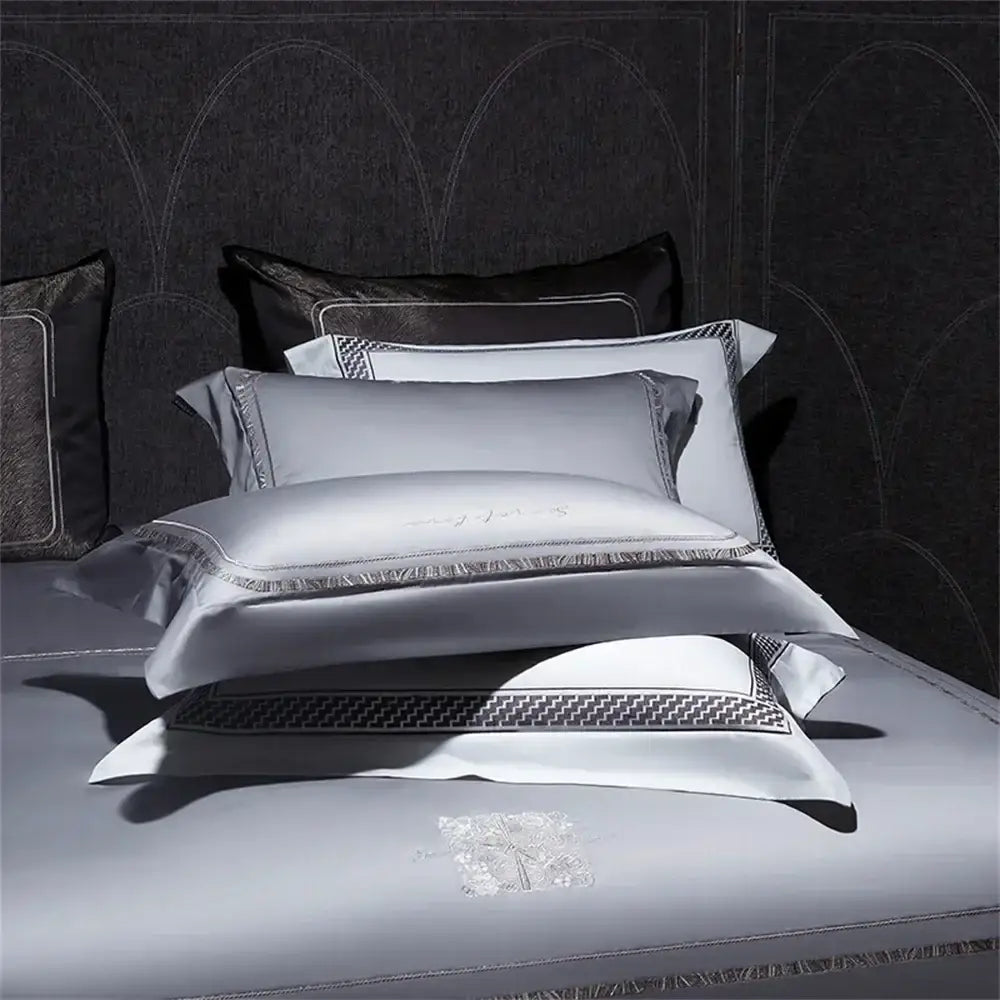 Stack of elegant silver-gray cotton satin jacquard pillowcases with geometric embroidery and black trim for bedding set decorbites