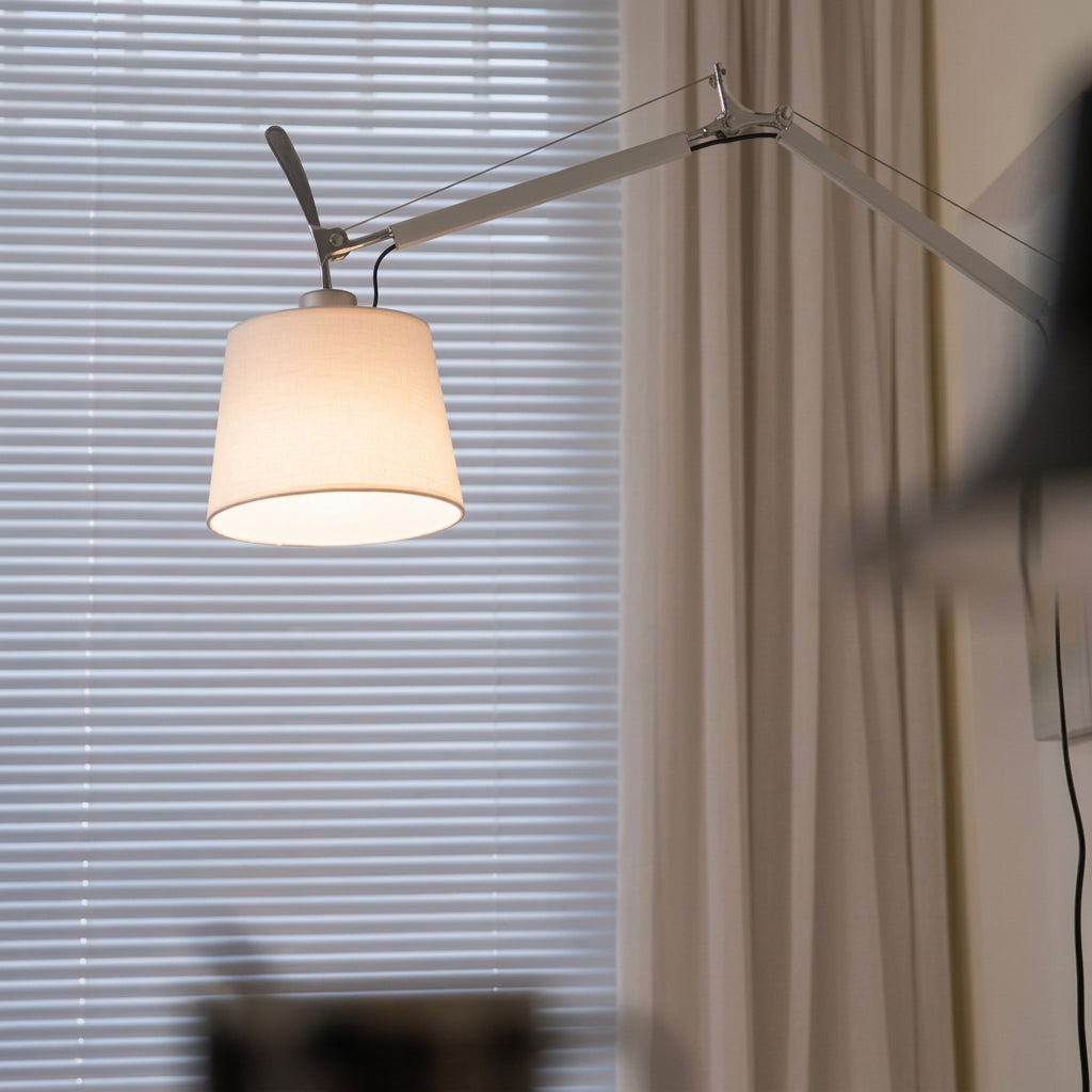 A sleek silver and cream decorbites adjustable wall lamp with long swing arm and off-white fabric shade for reading