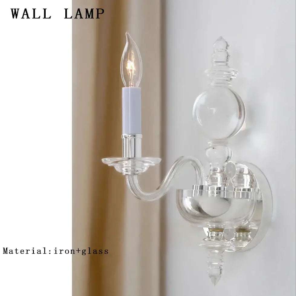 Clear glass wall lamp with silver iron base and curved arm featuring candle style bulb in decorbites crystal branch chandelier style