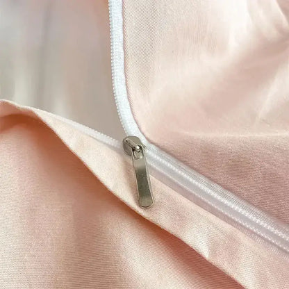A sleek silver zipper with a metallic pull tab on blush-pink satin fabric of a decorbites cotton king size bedding set
