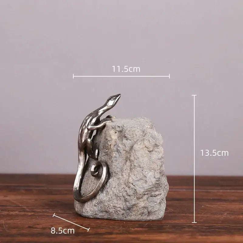 Silver gecko lizard resin figurine with metallic finish perched on textured gray stone base for living room decor
