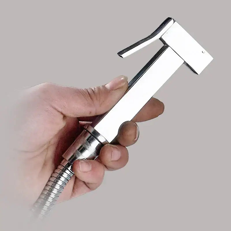 A sleek silver and golden bidet sprayer with chrome finish, textured grip, and flexible metal hose for bathroom use