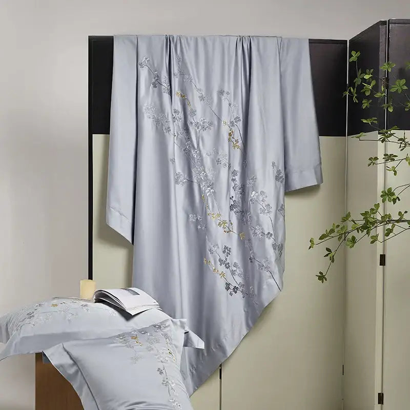 Light blue satin bedding set with silver and gold egyptian cotton flowers embroidery draped over dark screen