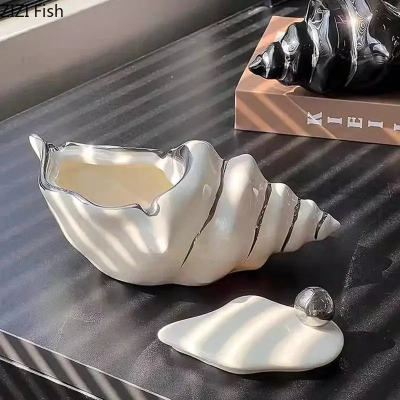 A glossy white ceramic conch ashtray with silver metallic accents and a matching lid for living room decorbites decor