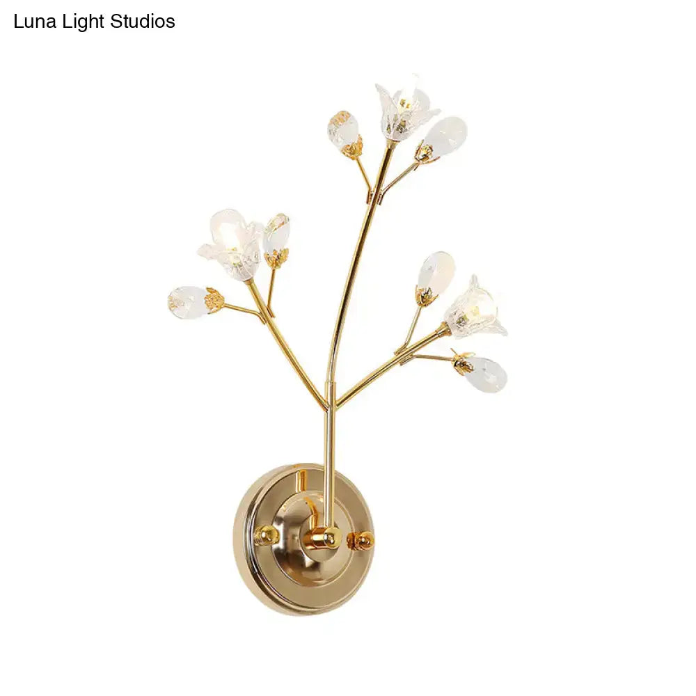 Gold-toned wall sconce with crystal flowers and slender branch-like arms for elegant bedroom lighting fixture
