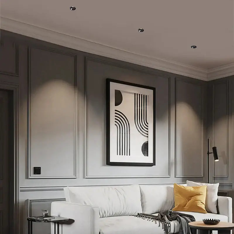 Black-framed abstract art with geometric curves hanging above sofa under sleek black glossy decorbites frameless led downlight