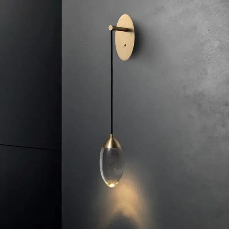 A sleek brass and crystal led wall light with a brushed gold base and teardrop glass shade for decorbites crystal led lighting