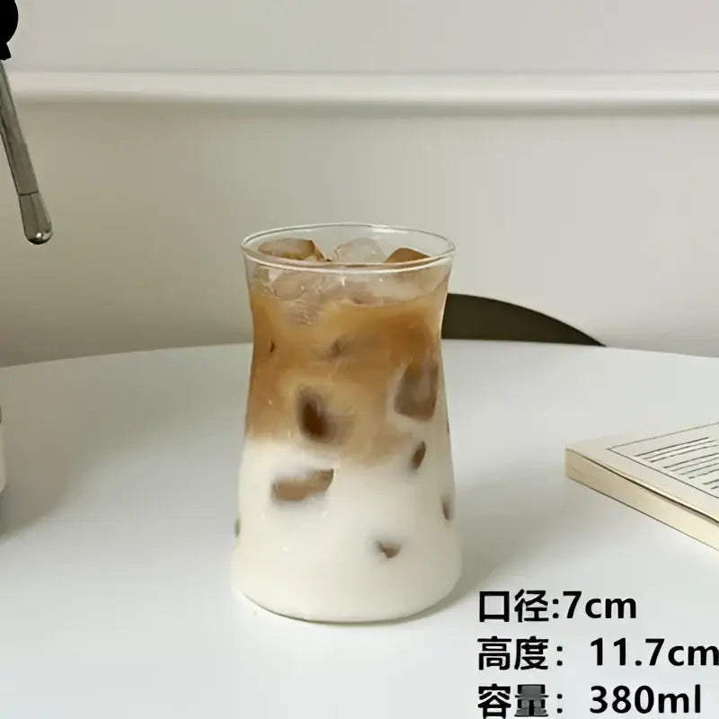 A sleek glass iced latte coffee cup with a wood band filled with iced latte coffee showing brown and white layers