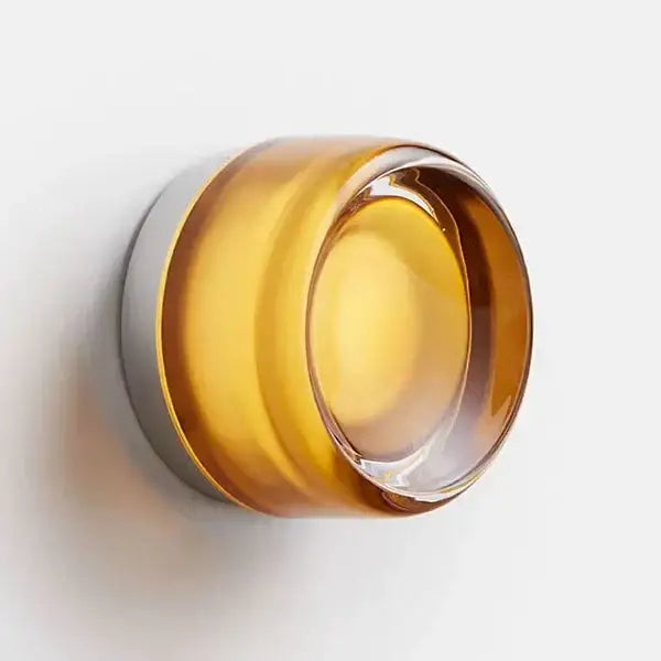 Amber-colored glass round wall sconce with sleek modern design and metallic silver base for bathroom use