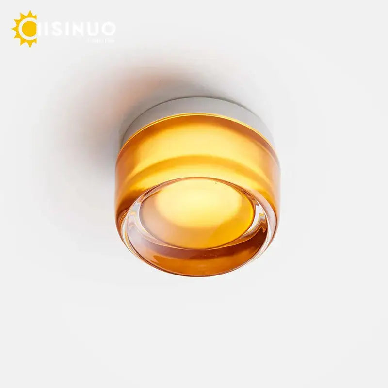 A modern amber glass round wall sconce with sleek metallic ring base designed for bathroom use