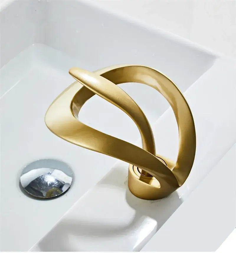 Golden sculptural basin faucet with flowing intertwined bands in sleek matte black brass waterfall design by decorbites black brass