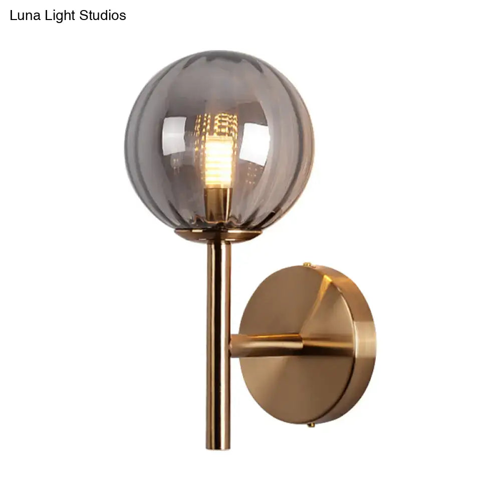 A sleek round wall lighting bedside sconce light with smoked glass globe and brass arm in red green amber tones