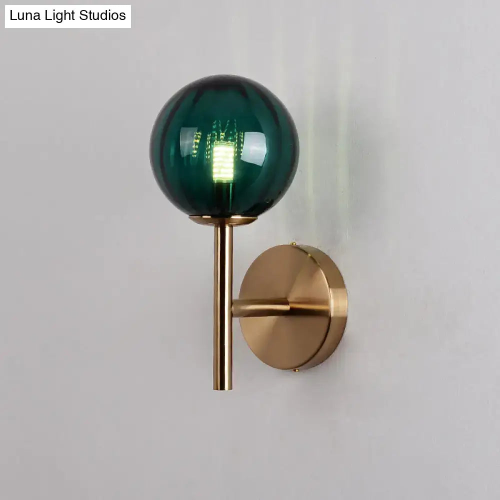 A sleek round wall lighting bedside sconce light with deep emerald green glass globe and brass stem in red green amber