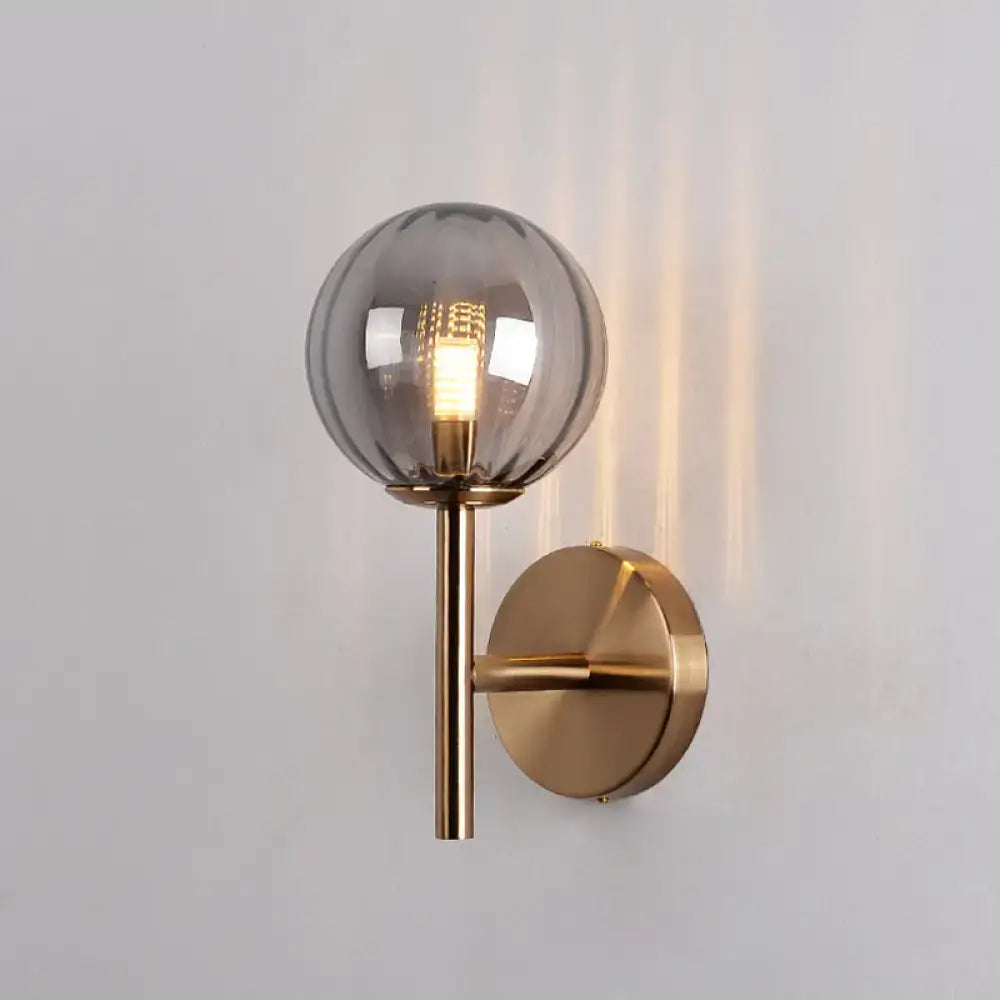 A sleek round wall lighting bedside sconce light with smoked glass globe and brass metal in red green amber colors