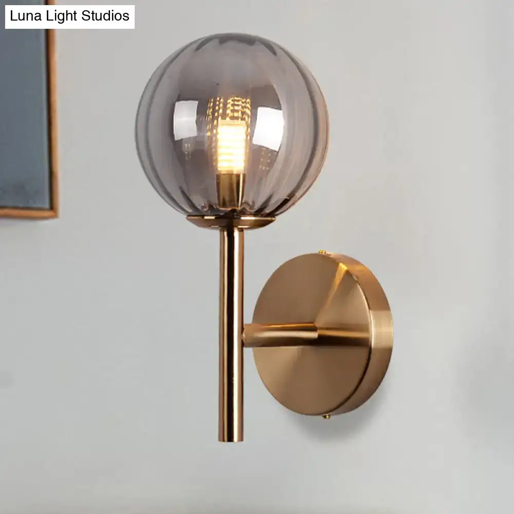 A sleek round wall lighting bedside sconce light with smoked glass globe and brushed brass hardware in red green amber