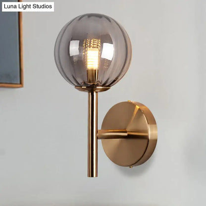 A sleek round wall lighting bedside sconce light with smoked glass globe and brushed brass hardware in red green amber