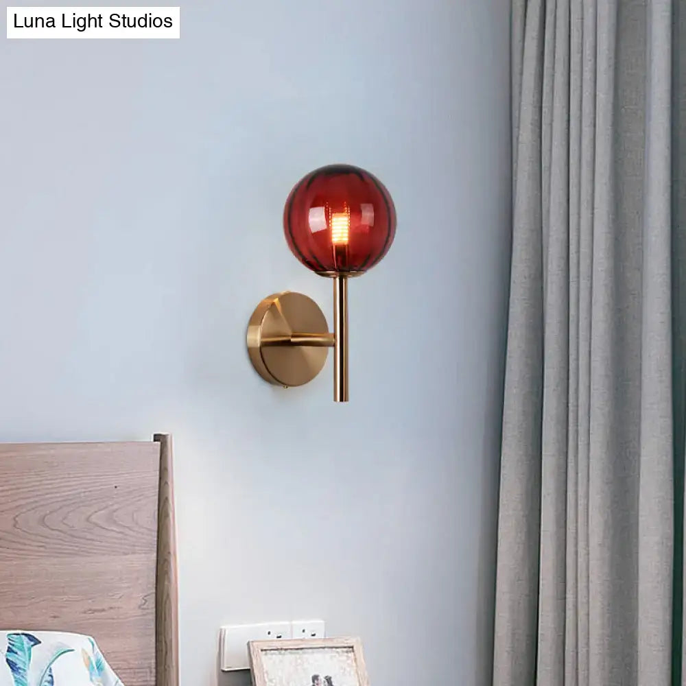 A sleek brass round wall lighting with a translucent amber glass globe bedside sconce light in red green amber colors