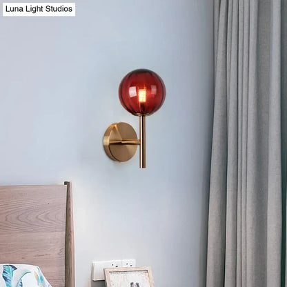 A sleek brass round wall lighting with a translucent amber glass globe bedside sconce light in red green amber colors
