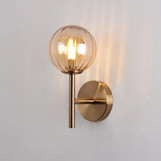A warm-toned spherical glass globe lamp with brass base for sleek round wall lighting red green amber bedside sconce light