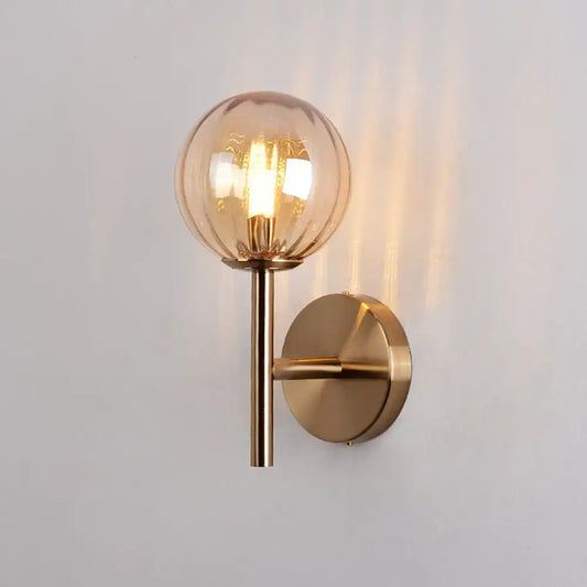 A warm-toned spherical glass globe lamp with brass base for sleek round wall lighting red green amber bedside sconce light