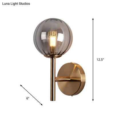 A modern round wall lighting with brushed brass finish and smoked glass globe bedside sconce light in red green amber