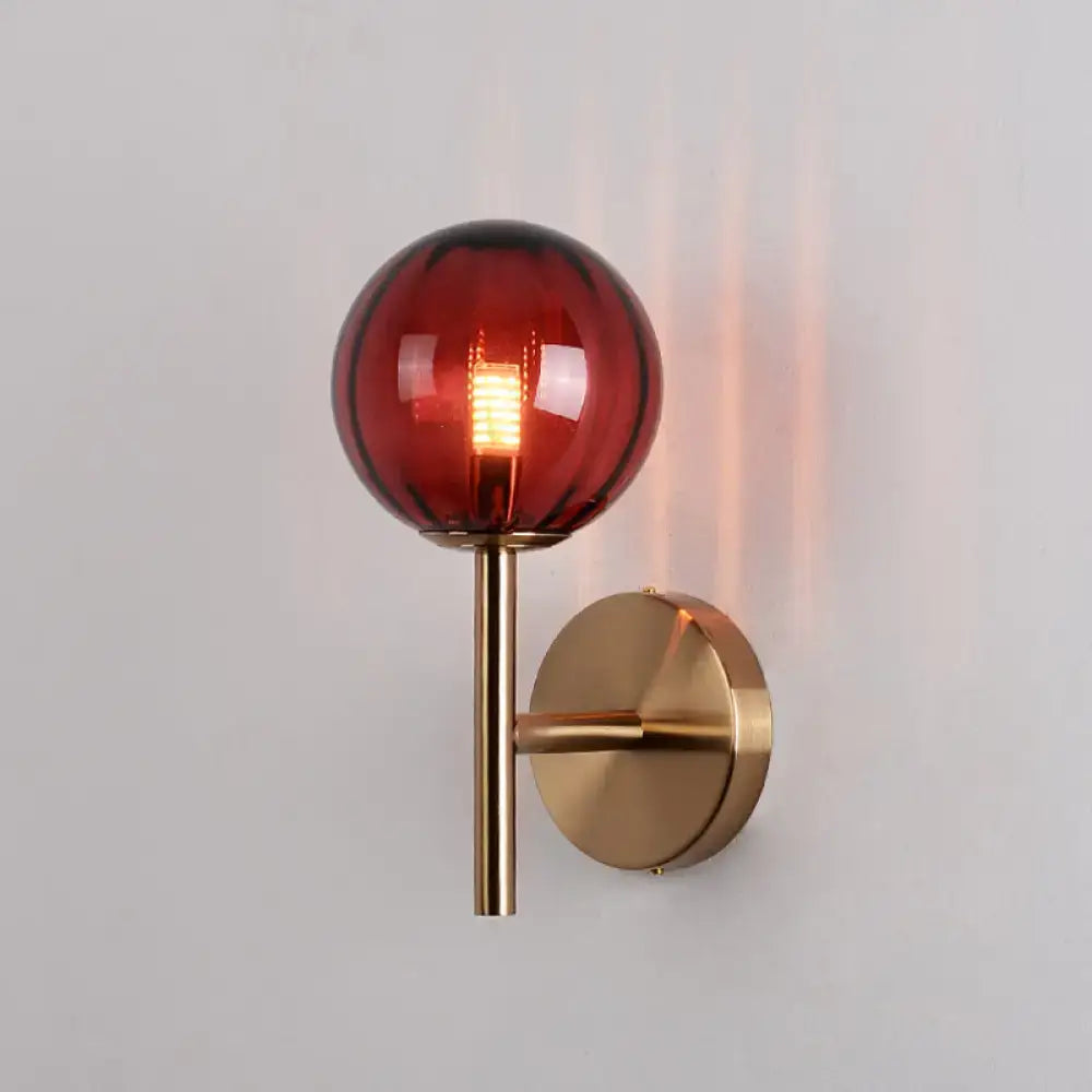 A sleek round wall lighting bedside sconce light with an amber glass globe on a brass stem and circular backplate