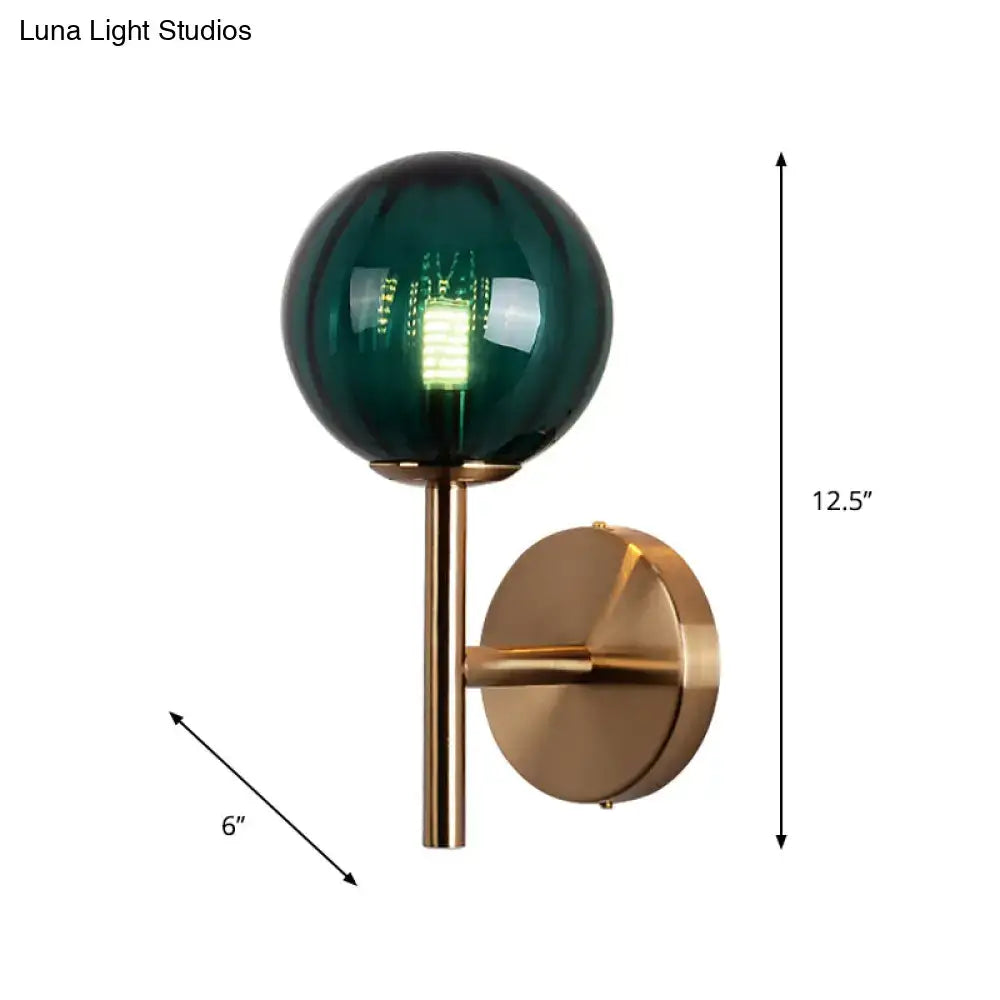 A sleek brass round wall lighting with a deep green glass globe and exposed filament bedside sconce light