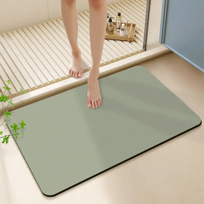 A sleek sage green matte diatom ooze bath rug with rounded corners and a black border for non-slip use