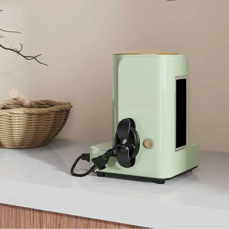 Mint green electric coffee grinder with black cord and handle next to sleek silicone decorbites cord winder cable organizer