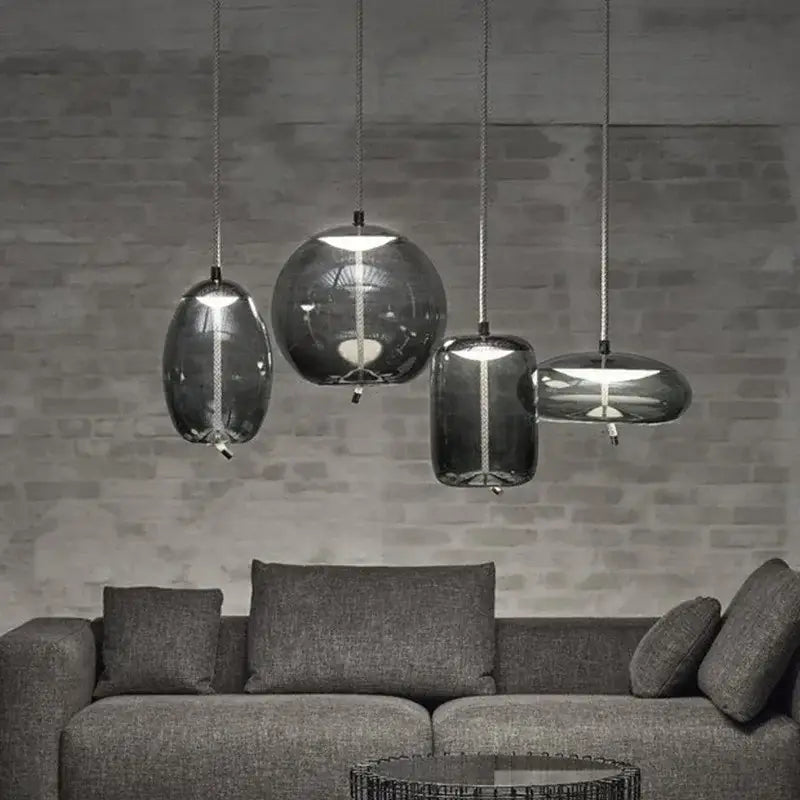 Set of four modern sleek smoked glass led chandelier pendant lights with dark gray shades and metallic chains for living room