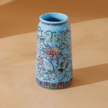 A small light blue ceramic vase with pink purple and gold floral patterns in handmade vintage Chinese enamel glaze