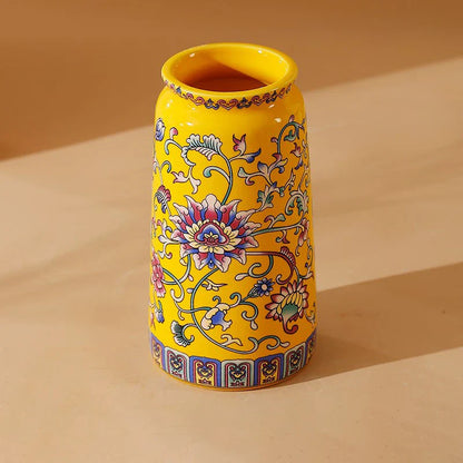 A vibrant yellow small ceramic vase with blue pink and green floral patterns for office and home decoration