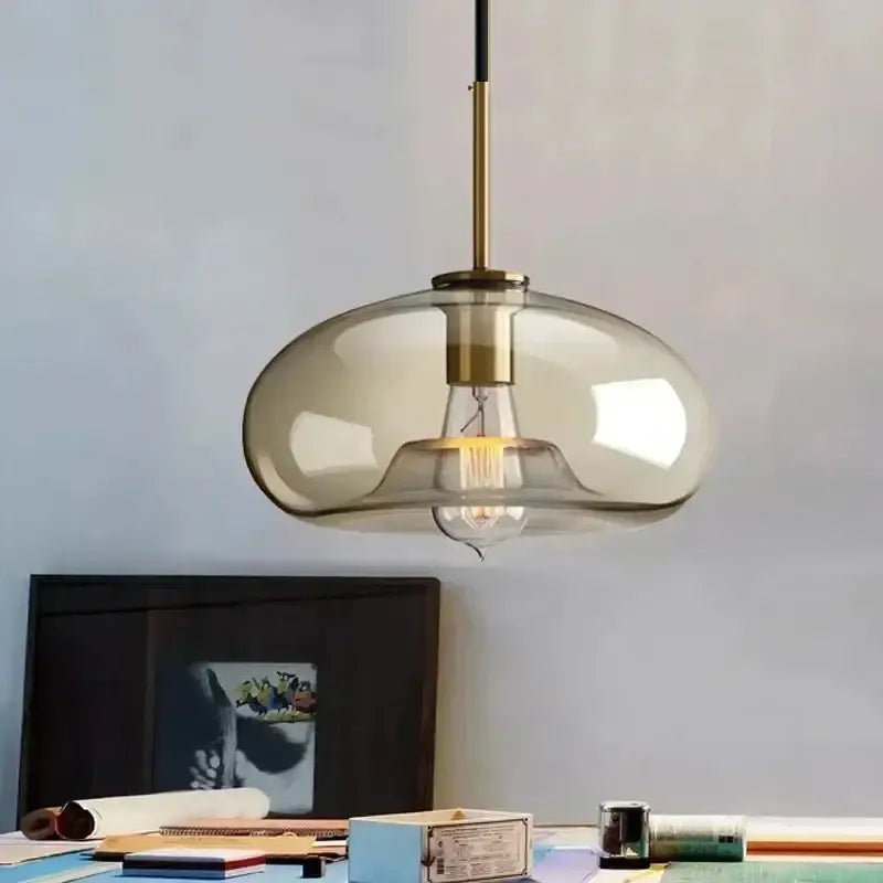 Smoked glass and brass pendant light with translucent shade and exposed filament bulb for dining room use