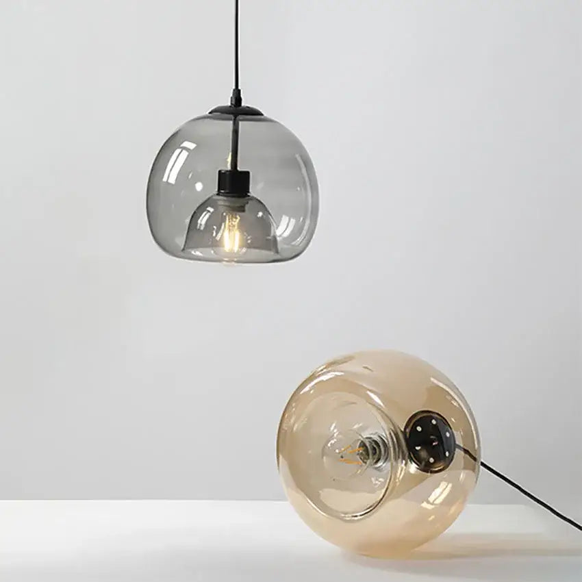 A sleek smoked glass pendant light and amber-toned table lamp in a dining room pendant lights trio