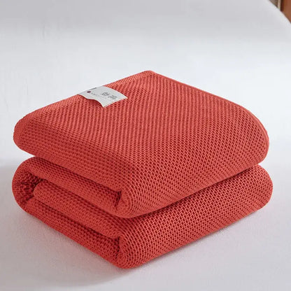 A neatly folded coral-colored knitted honeycomb towel blanket with a breathable weave for living room decorbites cotton honeycomb