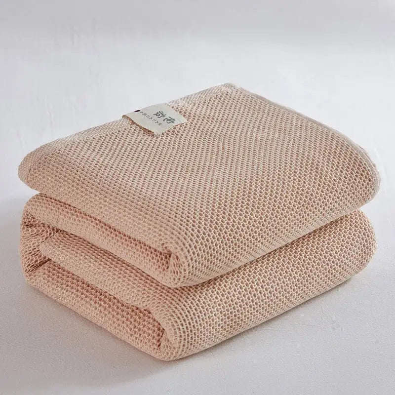 A soft beige cotton honeycomb towel blanket with waffle-weave texture neatly folded for living room couch decorbites decor