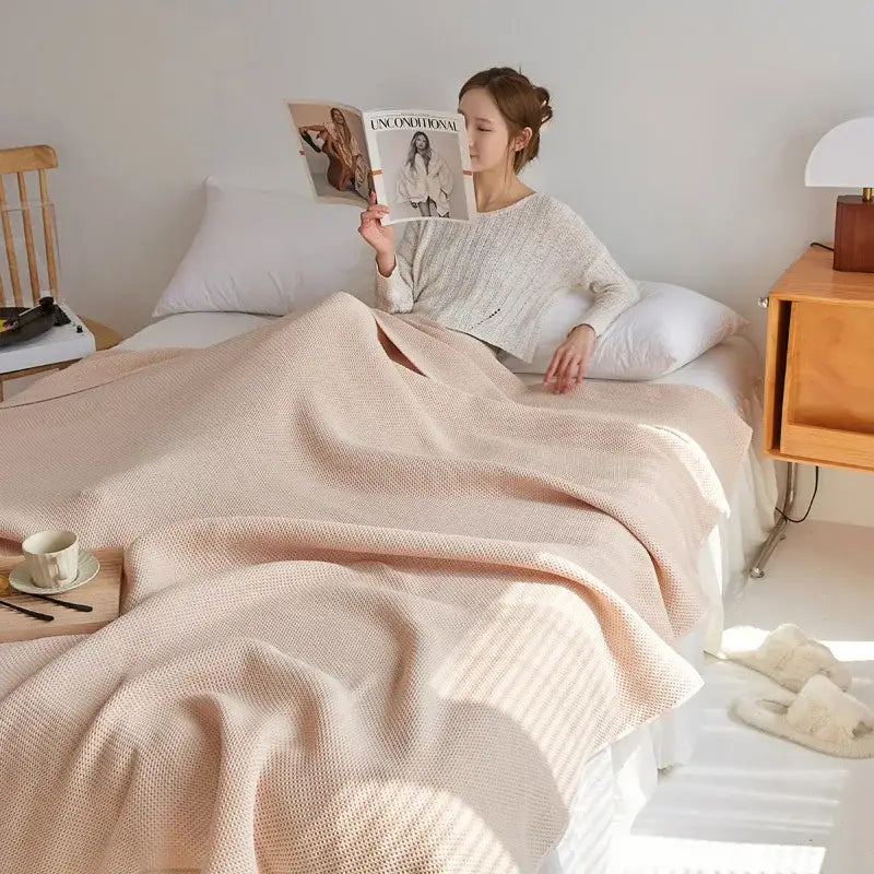 Soft blush pink knitted throw blanket draped over bed complementing decorbites cotton honeycomb towel blanket for living room couch
