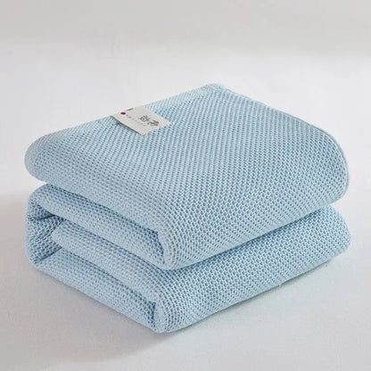 A soft light blue cotton honeycomb towel blanket with textured mesh pattern and neatly folded edges for living room decorbites