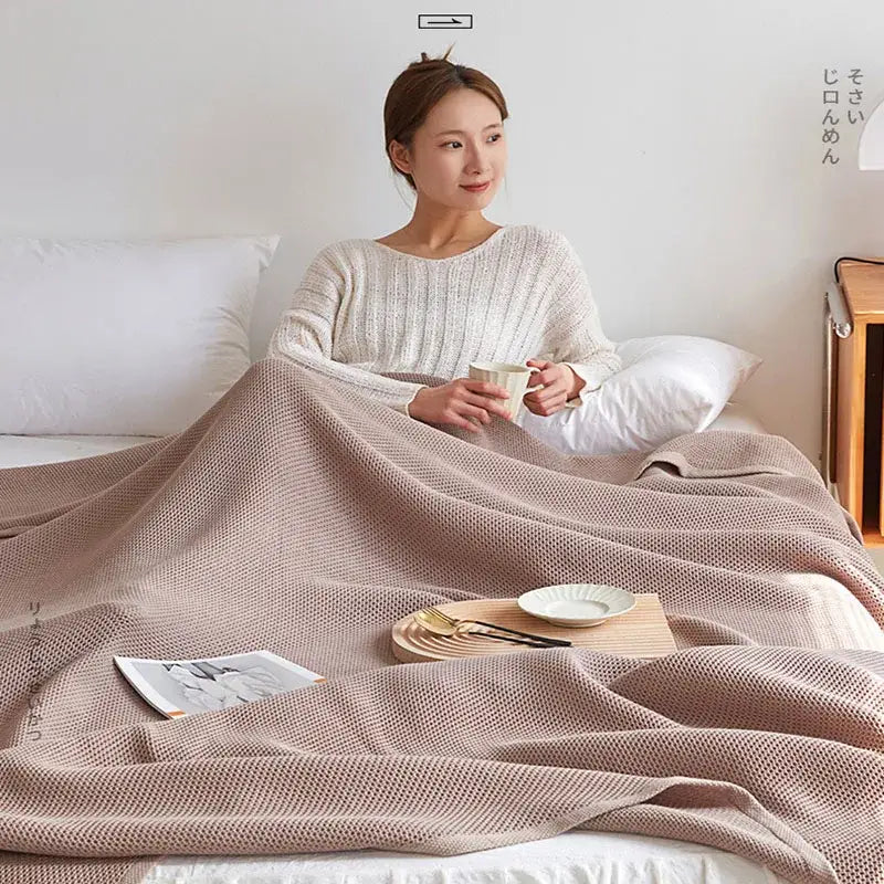 A soft beige decorbites cotton honeycomb towel blanket with textured weave draped over a person in bed