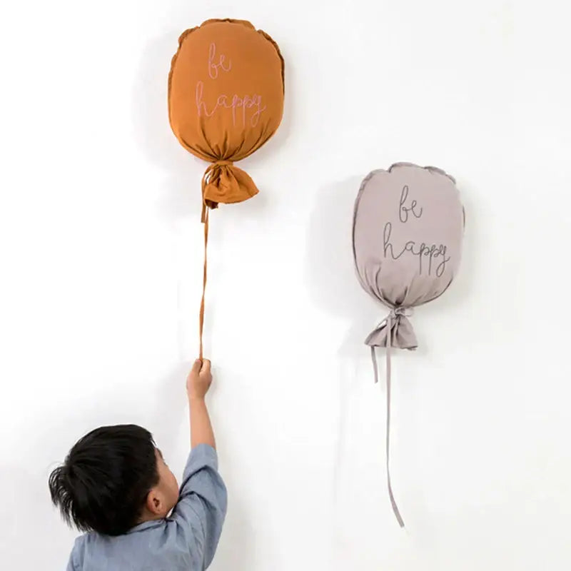 Soft cotton balloon wall hanging in orange and gray with be happy embroidered in pink for kids room decor