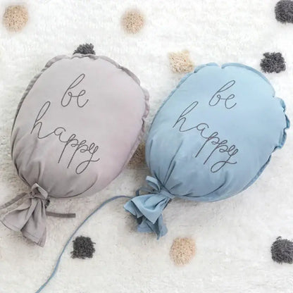 Soft pastel-colored cotton balloon wall hanging with be happy embroidery and tied fabric ends for kids room decor